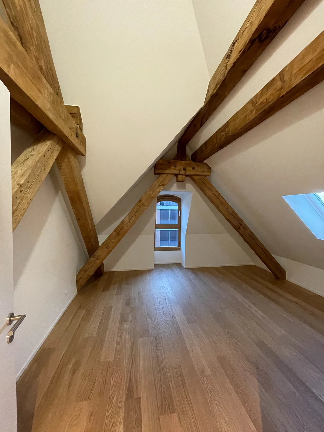 Pièce mansardée terminée, murs clairs et poutres en bois visibles