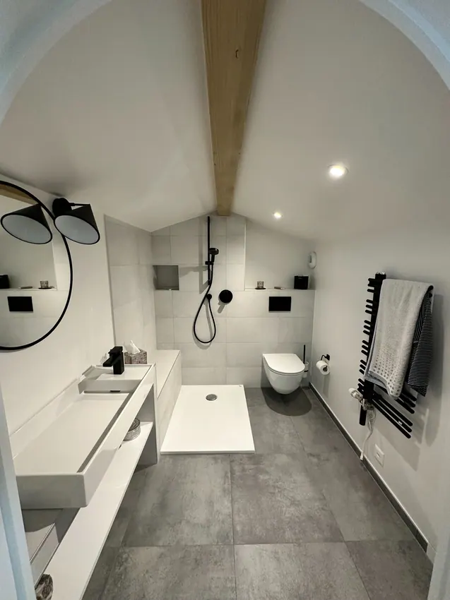 Salle d’eau mansardée avec murs blancs et plafond travaillé